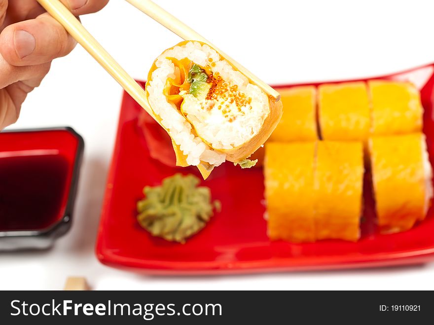 Men's hand holding sushi served on a plate. White background