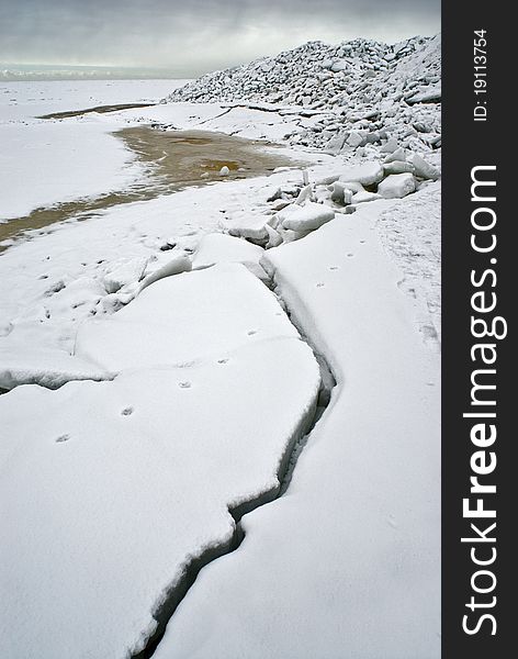 Ice at the sea coast white grey dark crack line season water horizon