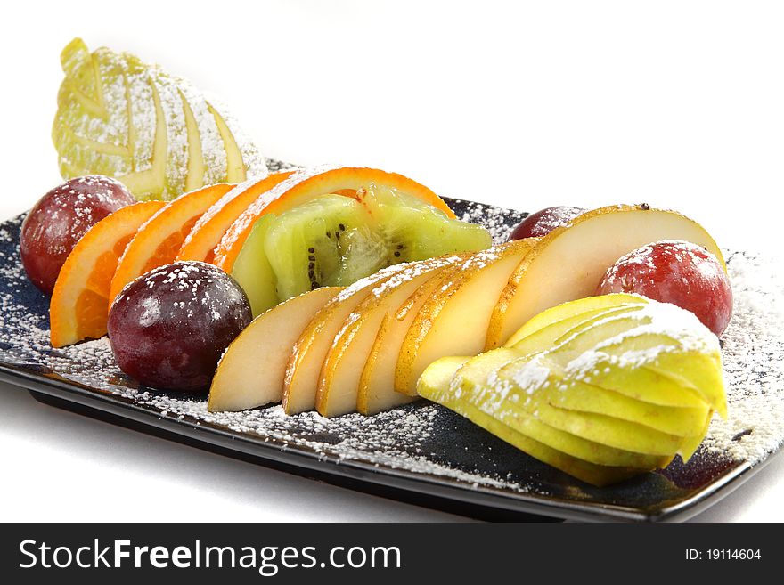 Cutting from different tropical fruit on a black rectangular plate