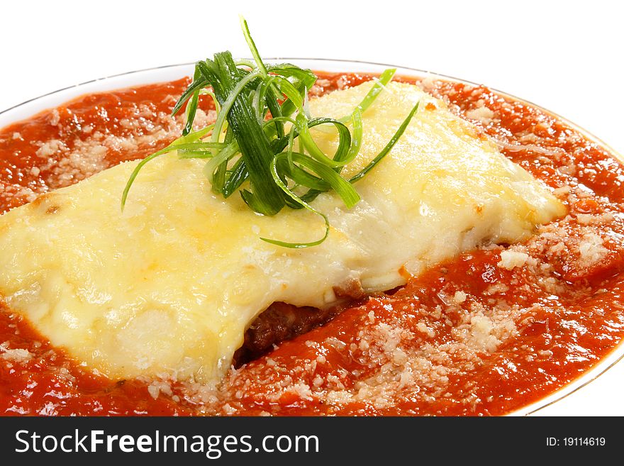 Portion of a lasagna in sauce on a white plate