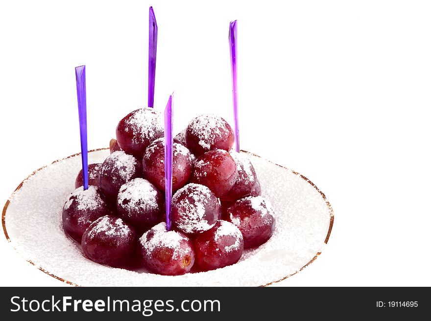 Red grapes on the white plate, strewed by powdered sugar