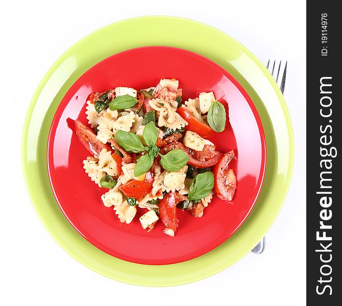 Salad - made of farfalle pasta, tomato, salami, bell pepper and mozzarella, decorated with basil, and a fork