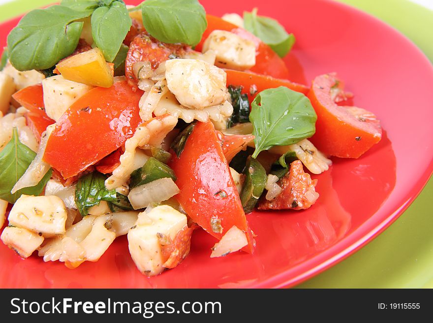 Salad - made of farfalle pasta, tomato, salami, bell pepper and mozzarella, decorated with basil