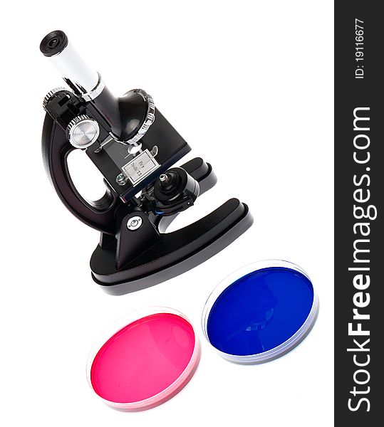 A microscope with two petri dishes containing bright red and blue liquids. A microscope with two petri dishes containing bright red and blue liquids