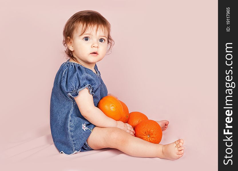Portrait of the child with oranges on a pink background in studio. Portrait of the child with oranges on a pink background in studio