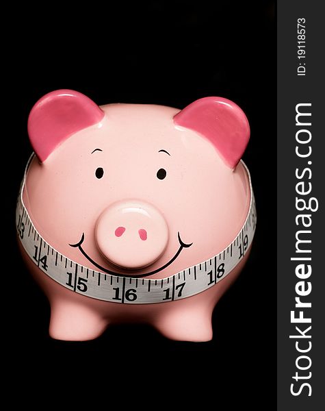 Piggy bank with tape measure isolated on black