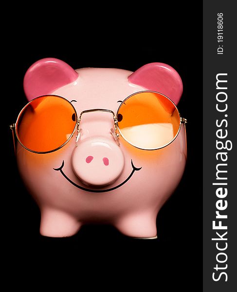 Piggy bank with sunglasses isolated on black