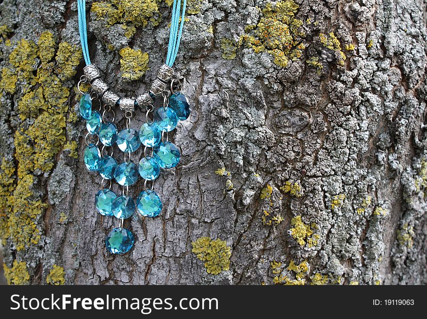 Blue gem necklace against a mossy tree. Blue gem necklace against a mossy tree