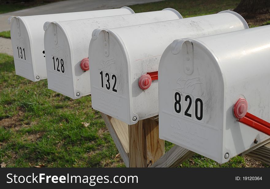 White mailboxes on a wooden post with closed doors and red flags that are in the down position. White mailboxes on a wooden post with closed doors and red flags that are in the down position.