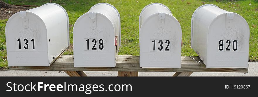 Front view of white mailboxes with green grass in the background. Front view of white mailboxes with green grass in the background.