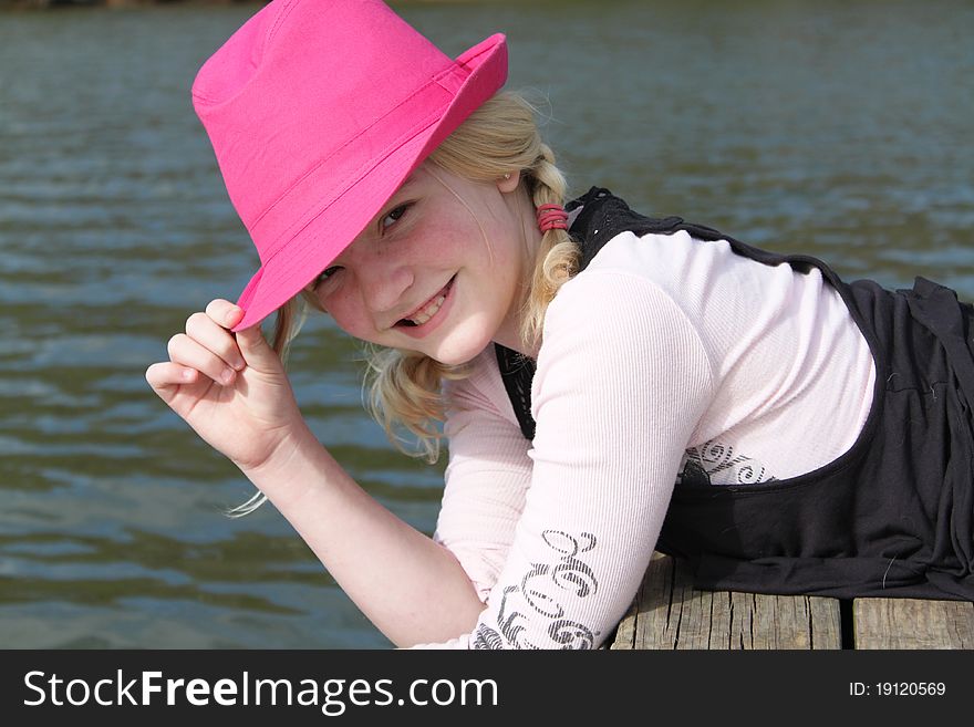 Young girl with a pink hat posing on the dock. Young girl with a pink hat posing on the dock.