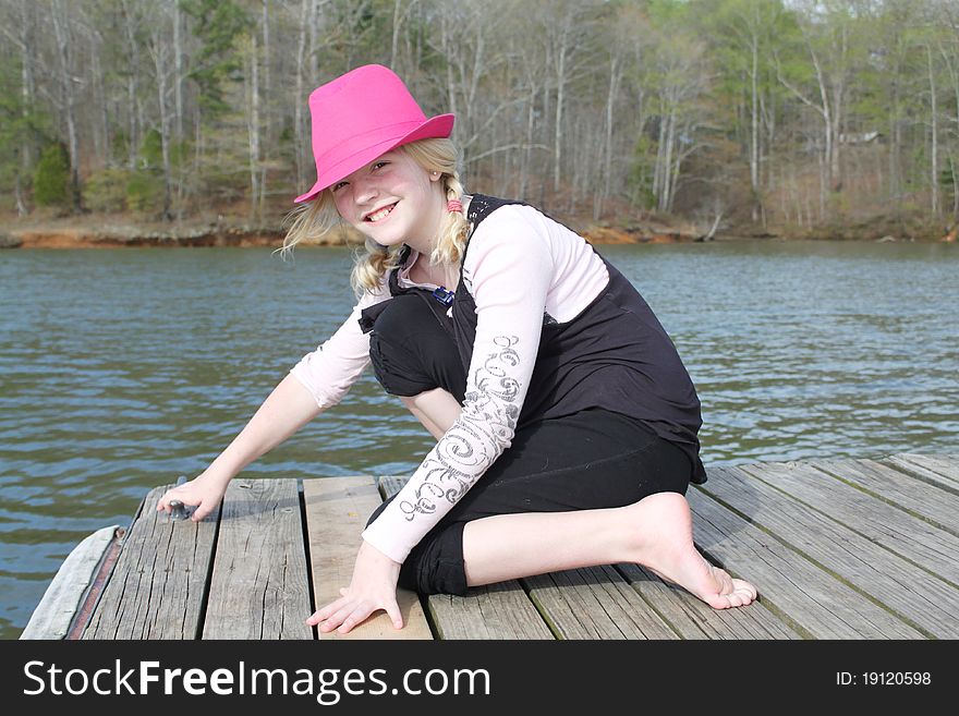 Girl in a pink hat on a wooden dock. Girl in a pink hat on a wooden dock.