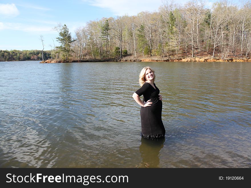 Beautiful pregnant woman standing in the water in a natural setting. Beautiful pregnant woman standing in the water in a natural setting.
