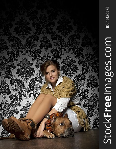 Young and beautiful girl  with American Staffordshire Terrier sitting on brown floor. Young and beautiful girl  with American Staffordshire Terrier sitting on brown floor