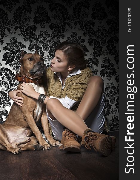 Young and beautiful girl with American Staffordshire Terrier sitting on brown floor