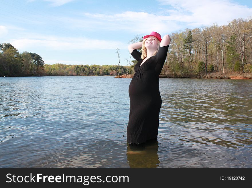 Happy pregnant woman standing in water at the edge of a beautiful lake. Happy pregnant woman standing in water at the edge of a beautiful lake.