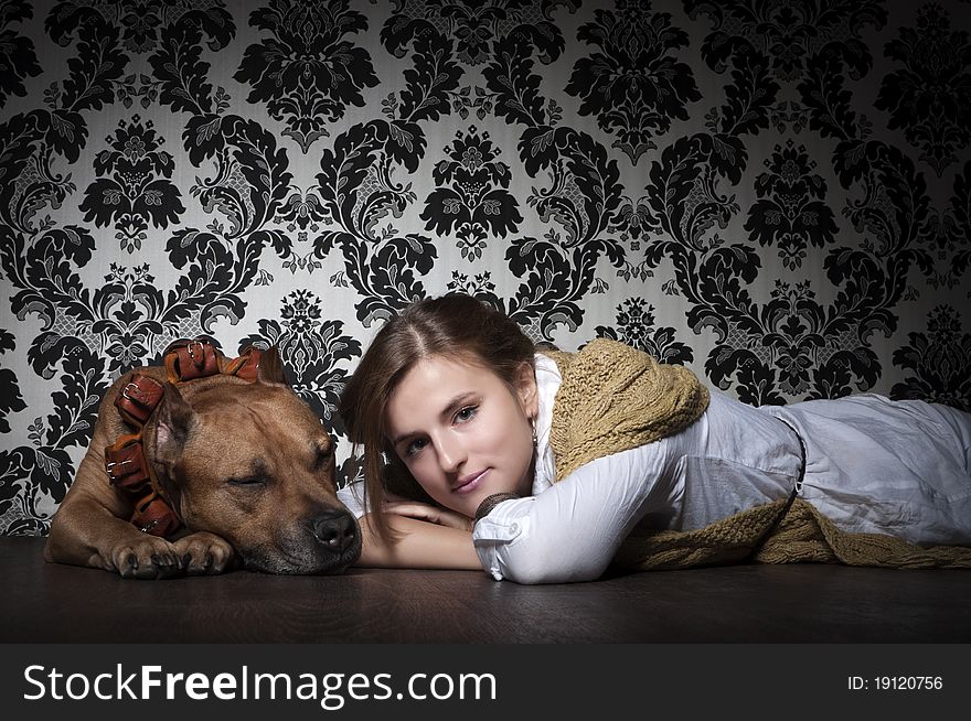 Young and beautiful girl  with American Staffordshire Terrier lying on a brown floor. Young and beautiful girl  with American Staffordshire Terrier lying on a brown floor