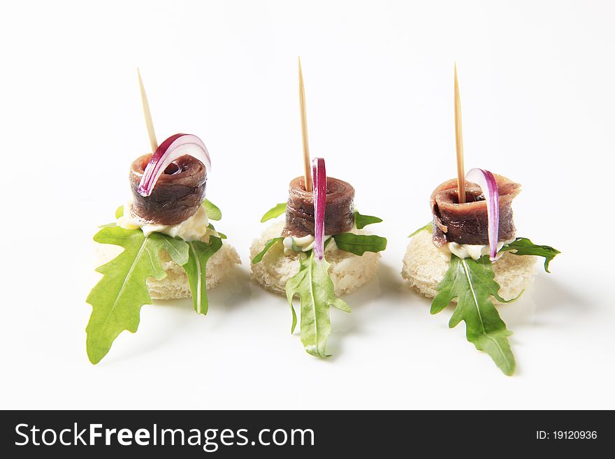 Anchovy canapes garnished with arugula and onion