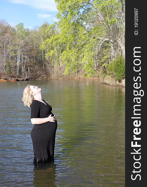Beautiful pregnant woman standing in the water with her head thrown back. Beautiful pregnant woman standing in the water with her head thrown back.