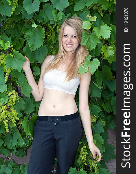 Portrait of the beautiful young blonde with grapes on a green background of foliage. Portrait of the beautiful young blonde with grapes on a green background of foliage
