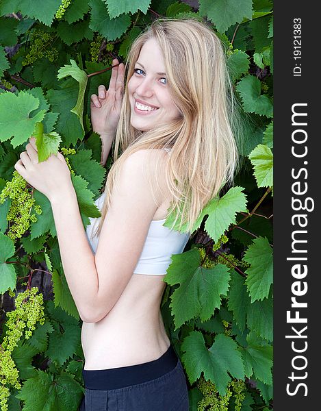 Portrait of an attractive girl in the leaves of grape