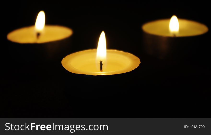 Three memorial candles in darkness