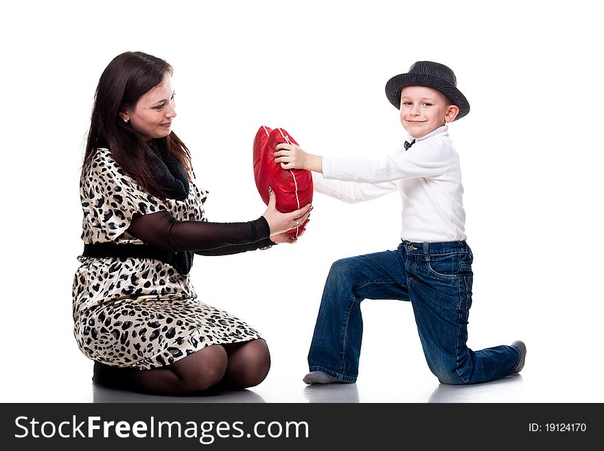 Cute boy giving red heart to his mother isolated on white