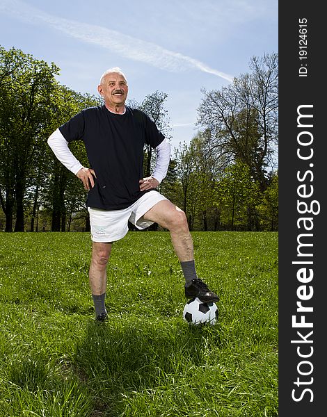 Senior football soccer player in the park standing on the soccer ball