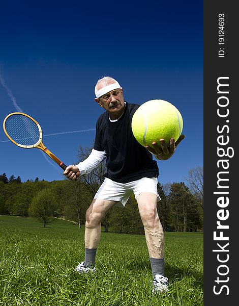 Senior man playing tennis with retro racquet