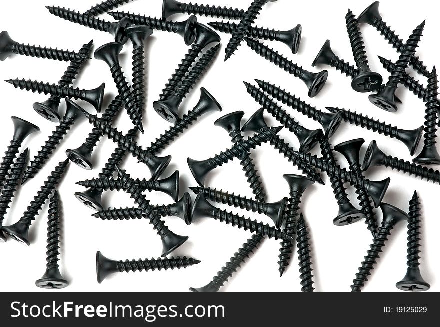 Black screws scattered randomly on a white surface