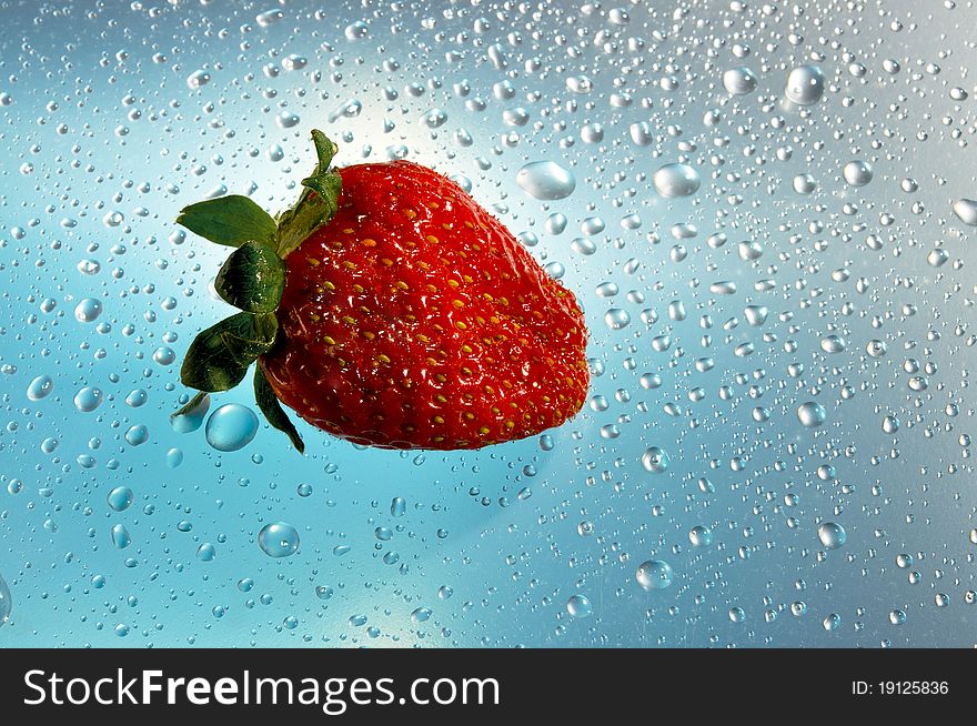 Strawberry red on a blue background with water drops