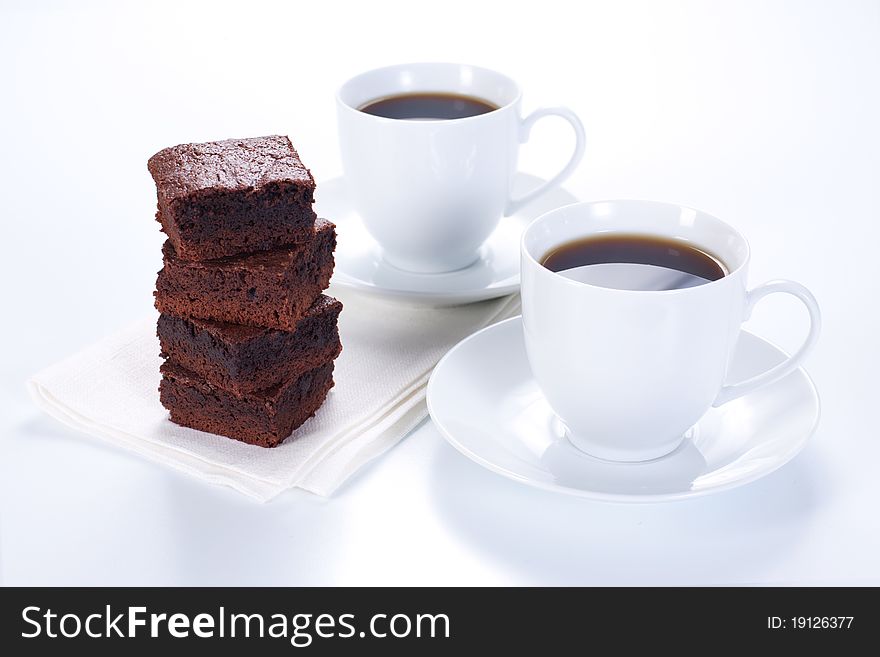 Chocolate brownies on white plate and two cups of coffee