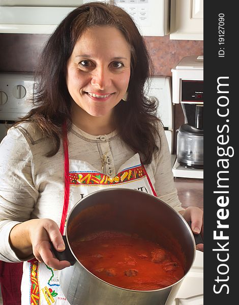 An woman displays the her pot of Italian style sauce and meatballs; a Sunday tradition. An woman displays the her pot of Italian style sauce and meatballs; a Sunday tradition.