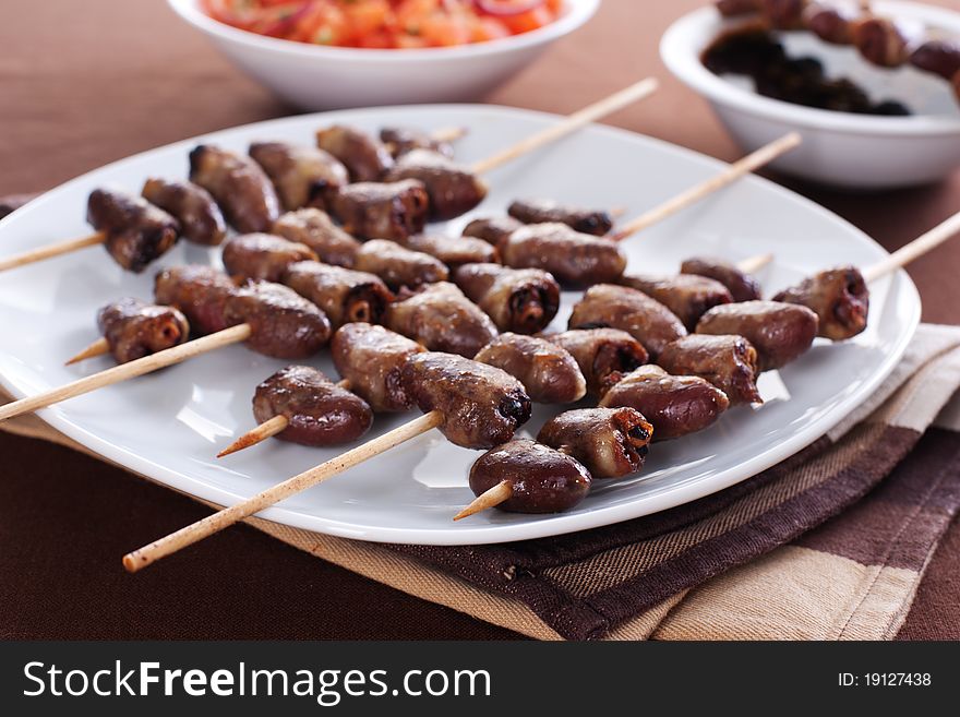 Grilled chicken hearts on skewers with soy sauce and salad.