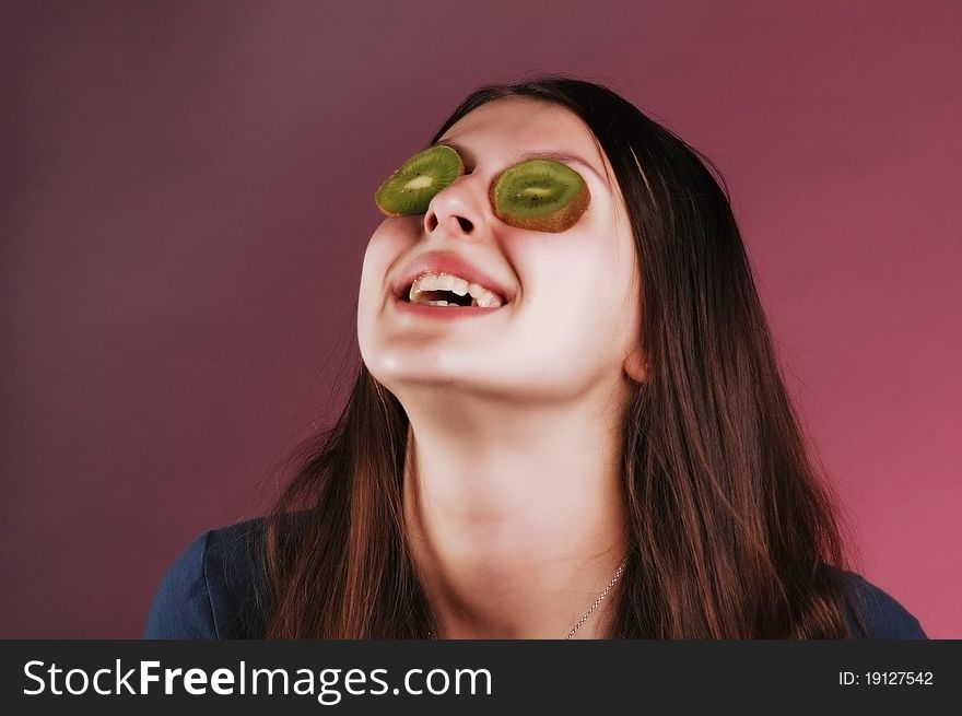 Pretty young woman holds kiwi in front of her eyes. Pretty young woman holds kiwi in front of her eyes