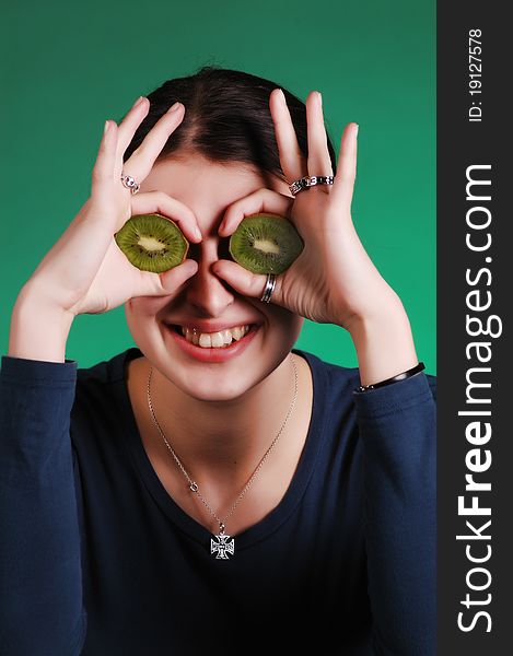 Young woman holds kiwi in front of her eyes. Young woman holds kiwi in front of her eyes