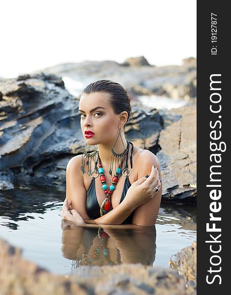 Beautiful brunette with bright makeup and  fashionable accessories posing in the sea. Beautiful brunette with bright makeup and  fashionable accessories posing in the sea