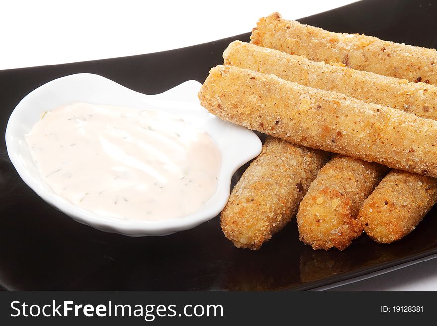 The roasted meat sticks on a black rectangular dish with white sauce