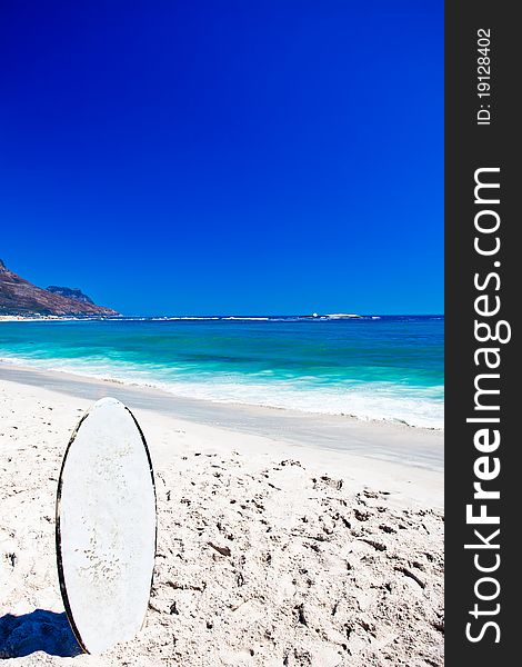 White skim board standing on the beach.