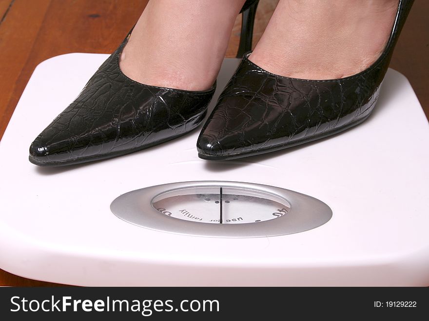 Black stilettos on a white bathroom scale. Black stilettos on a white bathroom scale