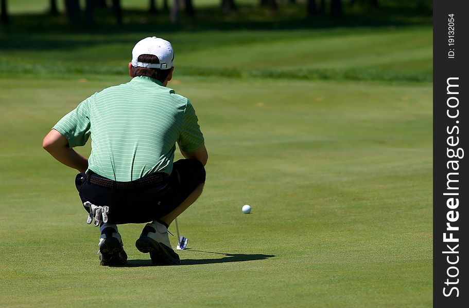 Golfer lines up his putt on the green as he prepares to putt.