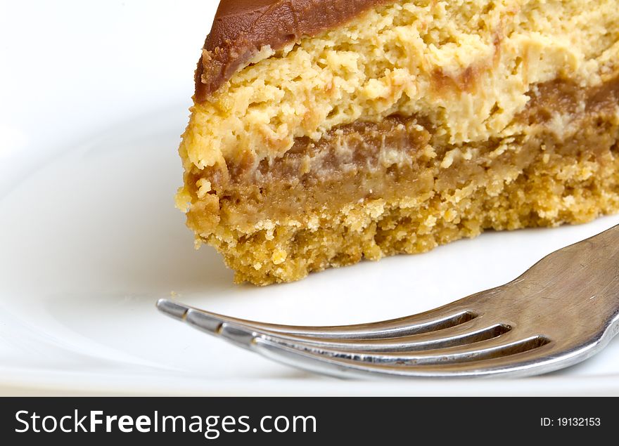 Chocolate Caramel Cheesecake on plate with fork isolated on white.