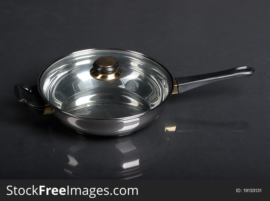 Metallic frying pan on black background