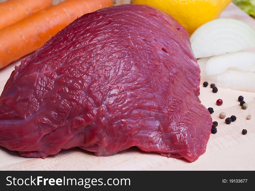 Fresh beef tenderloin and vegetables on cutting board, selective focus. Fresh beef tenderloin and vegetables on cutting board, selective focus.