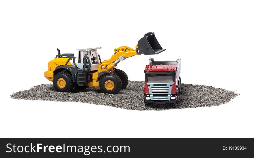 The heavy bulldozer of yellow color on a white background is loading of heavy dump-body truck. The heavy bulldozer of yellow color on a white background is loading of heavy dump-body truck