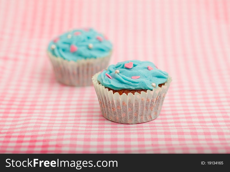 Delicious blue birthday cupcake against a pink background