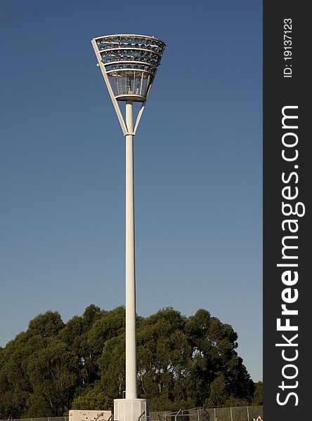 A tall floodlights stand against a blue sky background. A tall floodlights stand against a blue sky background