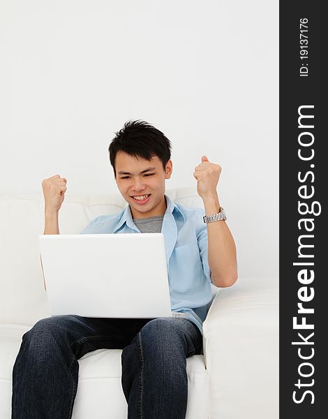 An excited Asian man with his laptop at home. An excited Asian man with his laptop at home