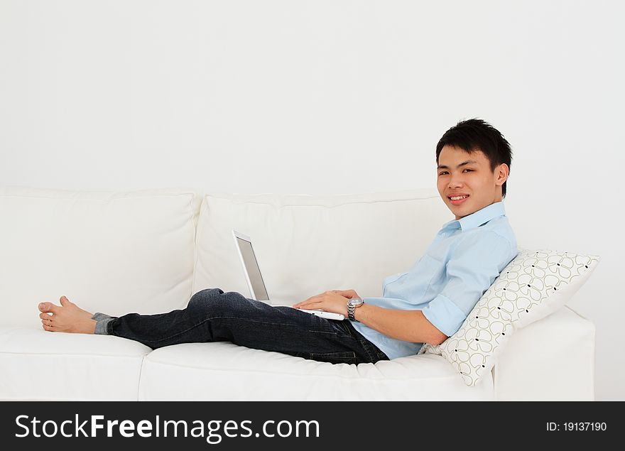 A man working with his laptop on a sofa. A man working with his laptop on a sofa