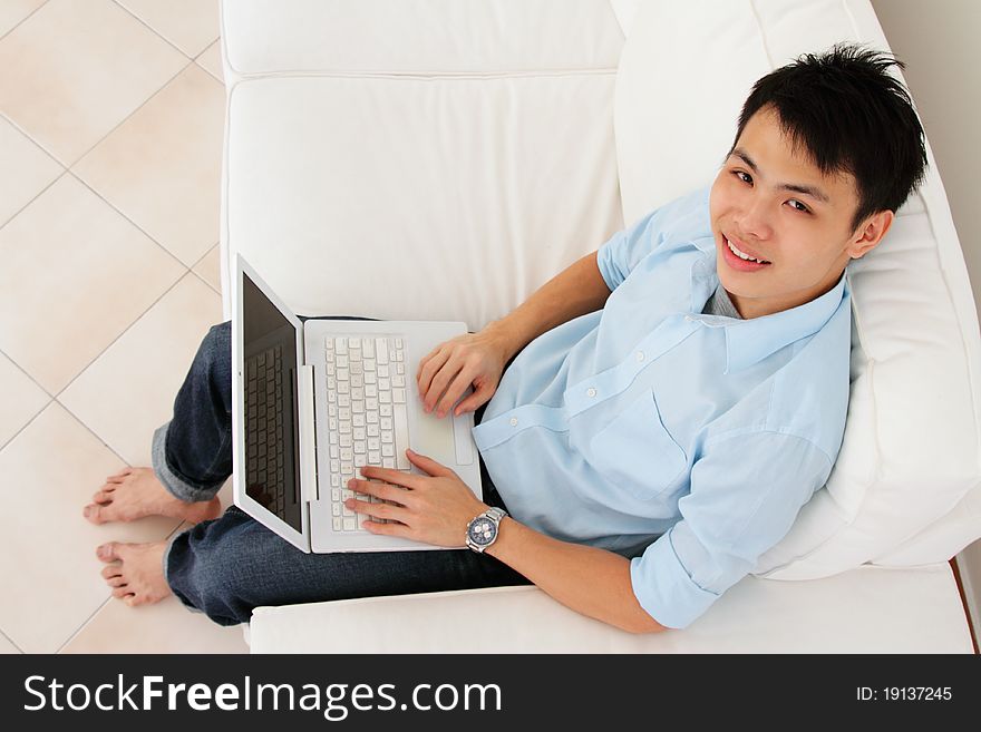 An Asian man working with his laptop at home. An Asian man working with his laptop at home